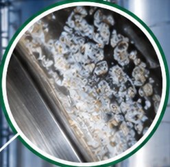 Detalhe ampliado de pedra de leite incrustada em superfície de aço inox